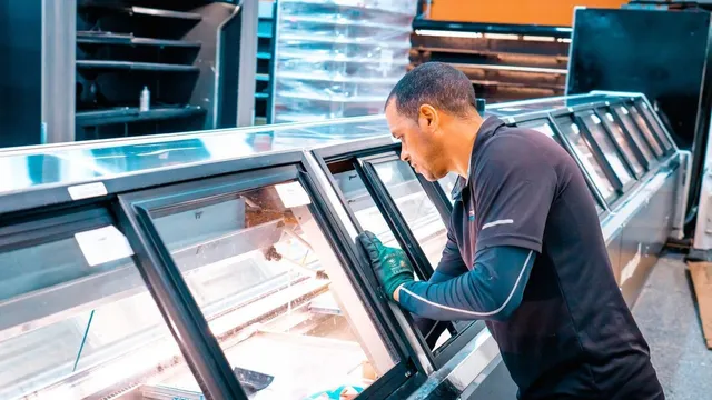 Technician working on open refrigerated display cases to improve energy efficiency