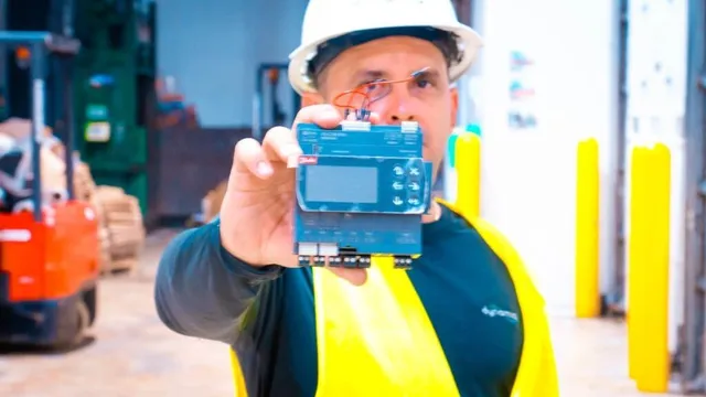 Dynamiq technician holding a smart controller for walk-in coolers and freezers